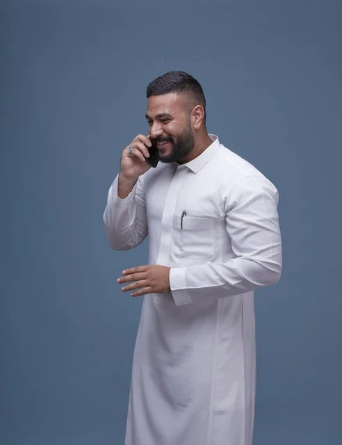 Saudi Man in White Thobe Talking on Smartphone