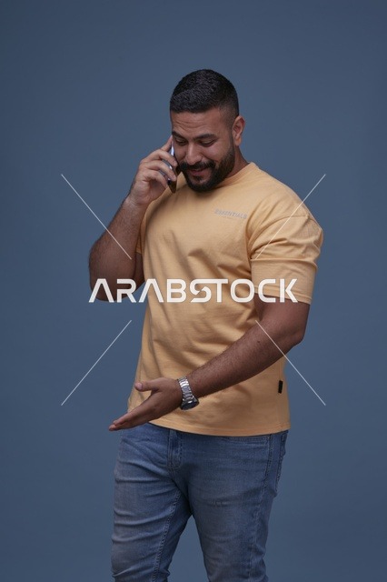رجل سعودي مبتسم يتحدث بالهاتف بملابس كاجوال