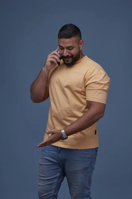 رجل سعودي مبتسم يتحدث بالهاتف بملابس كاجوال