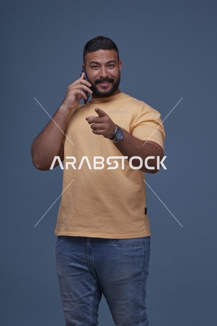 رجل سعودي مبتسم يتحدث بالجوال بملابس كاجوال