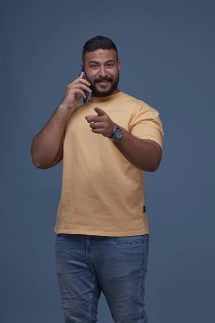رجل سعودي مبتسم يتحدث بالجوال بملابس كاجوال