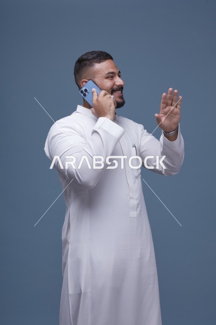 رجل سعودي بالثوب الأبيض يتحدث بالهاتف الذكي