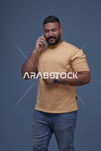 رجل سعودي مبتسم يتحدث بالجوال في الاستوديو