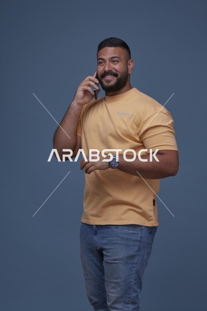 رجل سعودي مبتسم يتحدث بالهاتف بملابس كاجوال عصرية
