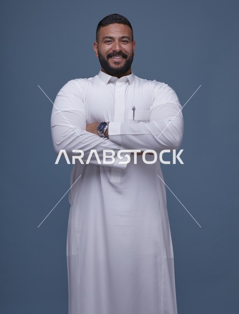 رجل سعودي مبتسم بالثوب الأبيض أمام خلفية زرقاء