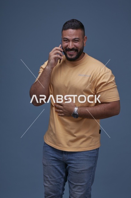 رجل سعودي مبتسم يتحدث عبر الهاتف في الاستوديو