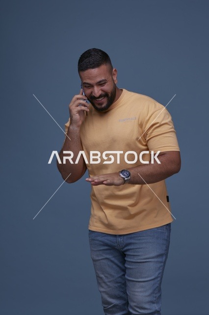 رجل سعودي يتحدث بالهاتف بملابس كاجوال مبتسم