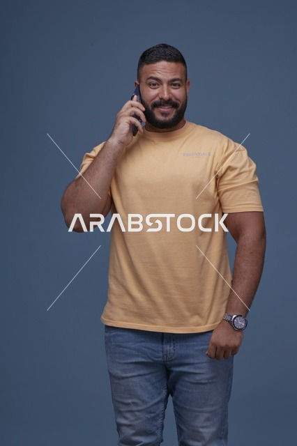رجل سعودي مبتسم يتحدث بالهاتف بملابس كاجوال صفراء