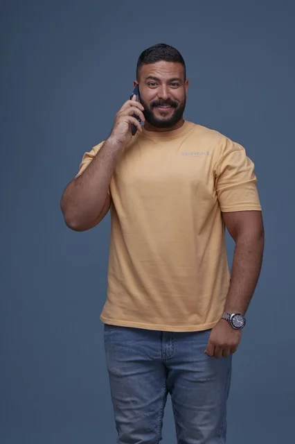 Smiling Saudi Man with Smartphone Wearing Casual Yellow Shirt