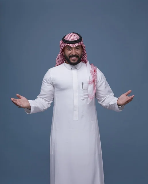 رجل سعودي بالزي التقليدي يفتح ذراعيه بالترحيب