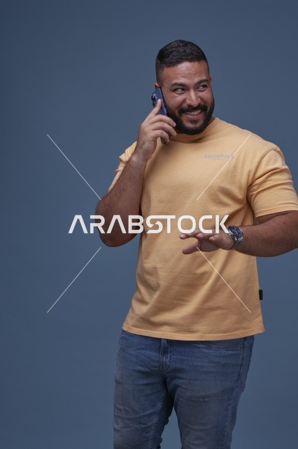 رجل سعودي مبتسم يتحدث عبر الهاتف بملابس كاجوال