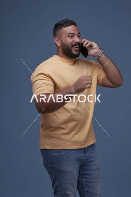رجل سعودي مبتسم يتحدث بالجوال بملابس كاجوال