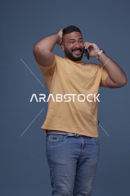 رجل سعودي مبتسم يتحدث عبر الهاتف بملابس كاجوال