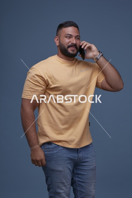 رجل سعودي مبتسم يتحدث بالهاتف الذكي بخلفية زرقاء