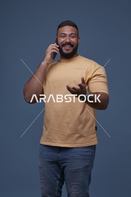 رجل سعودي مبتسم يتحدث عبر الهاتف المحمول بملابس كاجوال