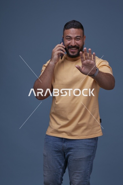 رجل سعودي مبتسم يتحدث عبر الهاتف الجوال بملابس كاجوال
