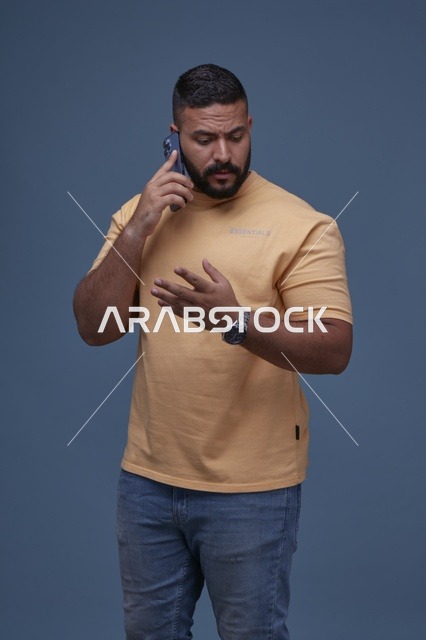 رجل سعودي يتحدث بالهاتف بملابس كاجوال صفراء