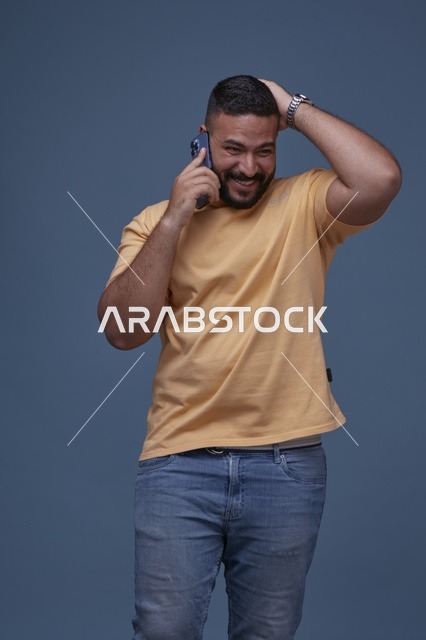 رجل سعودي مبتسم يتحدث عبر الهاتف بأسلوب كاجوال