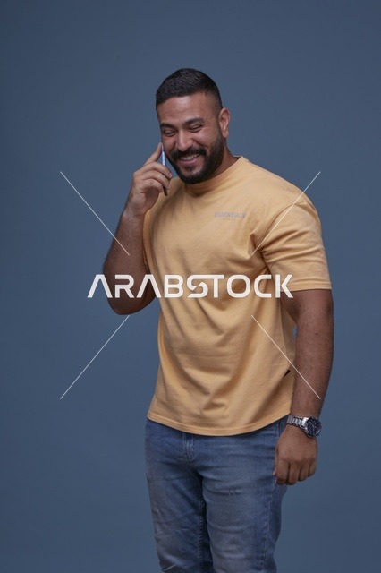 رجل سعودي مبتسم يتحدث عبر الهاتف بملابس كاجوال