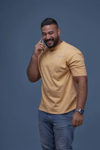 رجل سعودي مبتسم يتحدث عبر الهاتف بملابس كاجوال