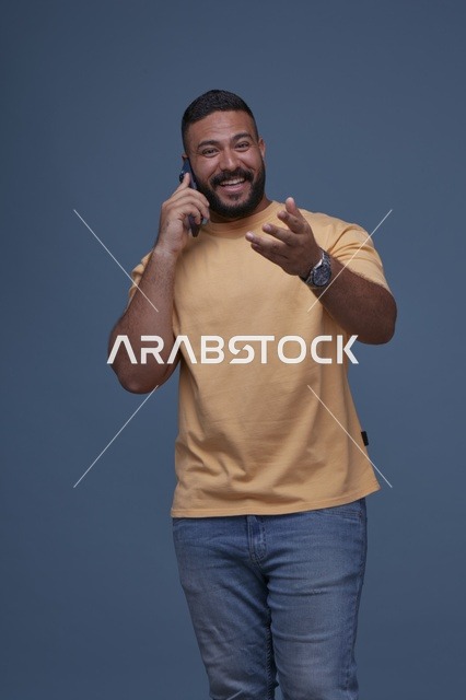 رجل سعودي مبتسم يتحدث عبر الهاتف الجوال بملابس كاجوال