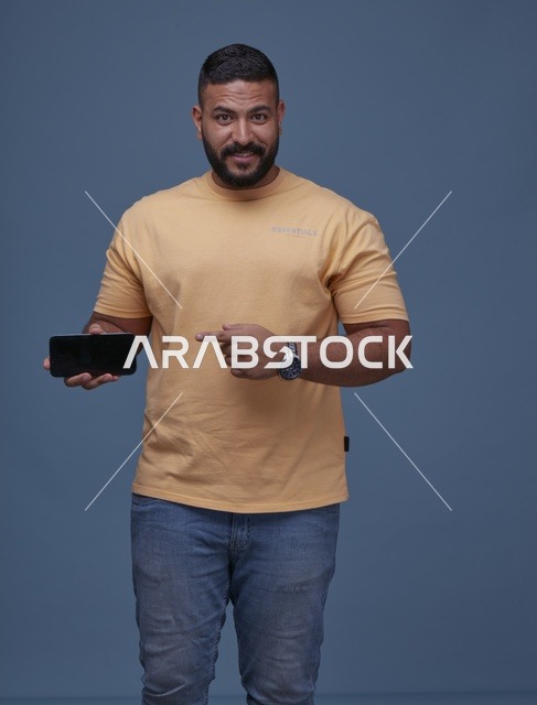 شاب سعودي بملابس كاجوال يلعب على الهاتف الذكي