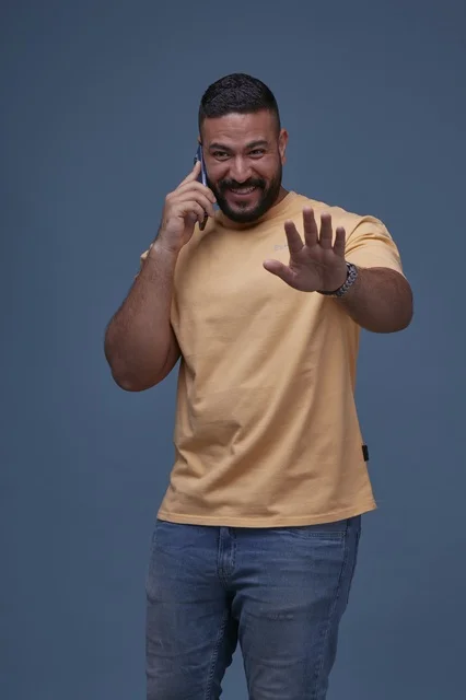 Smiling Saudi Man Talking on Smartphone with Stop Gesture