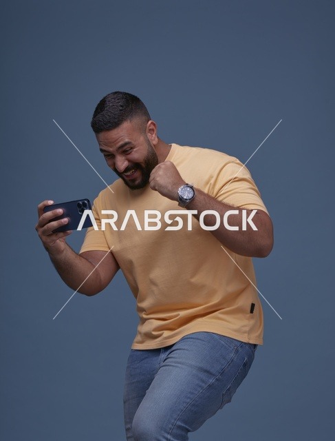 شاب سعودي بملابس كاجوال يلعب على الهاتف الذكي