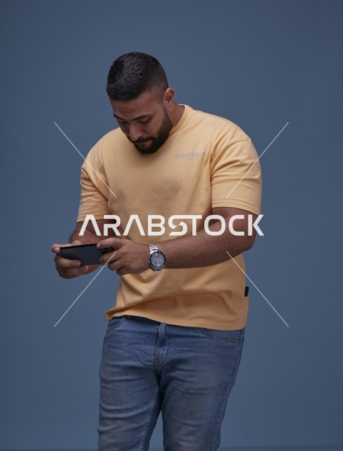 شاب سعودي يلعب على الهاتف الذكي بملابس كاجوال