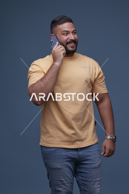 رجل سعودي مبتسم يتحدث عبر الهاتف الجوال بملابس كاجوال