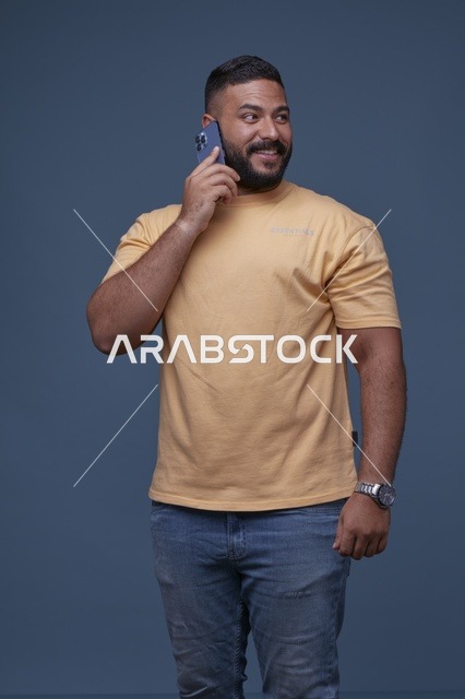 رجل سعودي يتحدث بالهاتف الجوال بملابس كاجوال صفراء