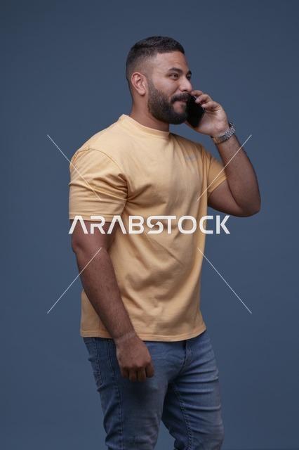 رجل سعودي يتحدث بالهاتف الذكي بملابس كاجوال صفراء