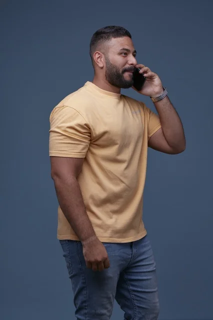 رجل سعودي يتحدث بالهاتف الذكي بملابس كاجوال صفراء