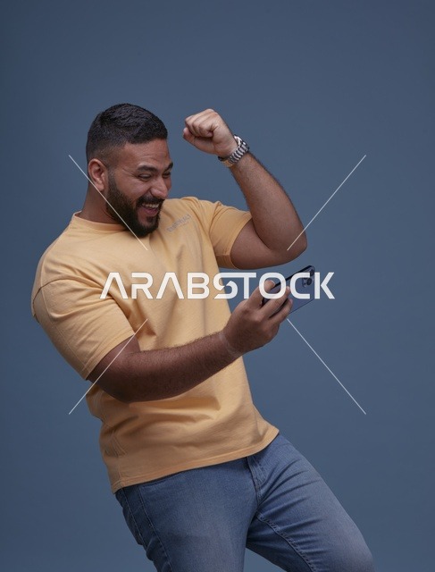 شاب سعودي بملابس كاجوال يلعب على الهاتف الذكي