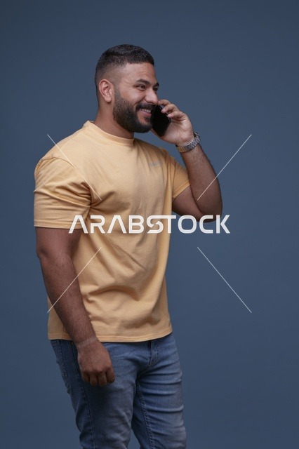 رجل سعودي مبتسم يتحدث عبر الجوال في الاستوديو