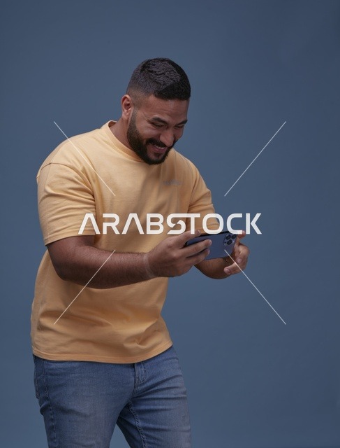 شاب سعودي يلعب بهاتفه على خلفية زرقاء
