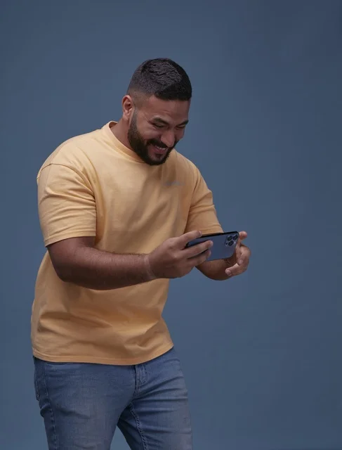Saudi Man Playing Mobile Game on Blue Background