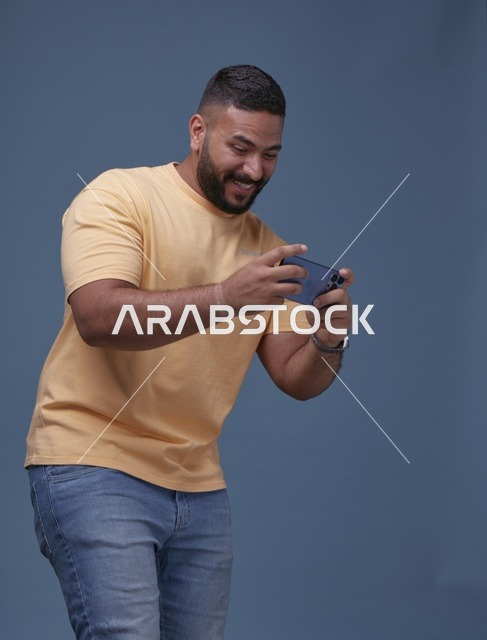 شاب سعودي يلعب بالهاتف الذكي بملابس كاجوال