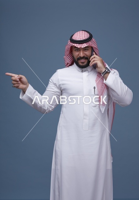 رجل سعودي يتحدث بالهاتف الذكي ويشير للجانب