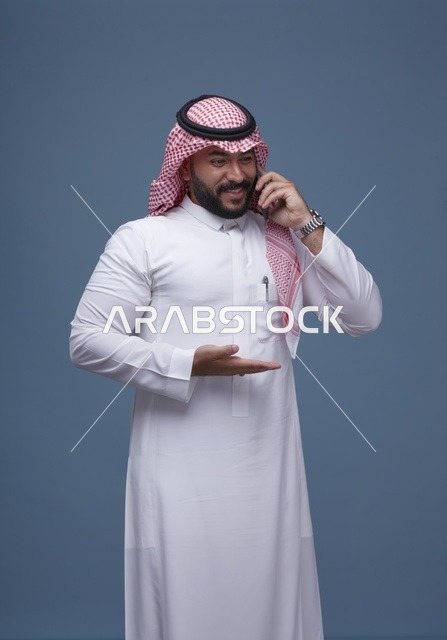 رجل سعودي مبتسم يتحدث بالهاتف الذكي في الاستوديو