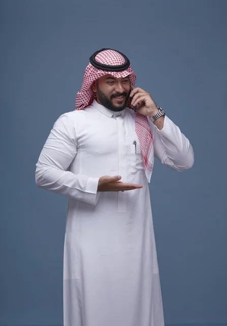 رجل سعودي مبتسم يتحدث بالهاتف الذكي في الاستوديو