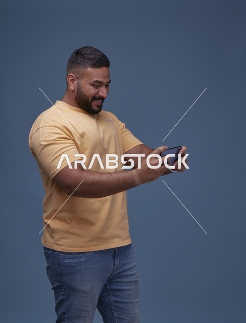 شاب سعودي يلعب بهاتفه الذكي بملابس كاجوال يومية
