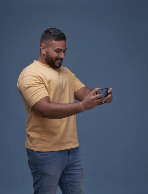 شاب سعودي يلعب بهاتفه الذكي بملابس كاجوال يومية
