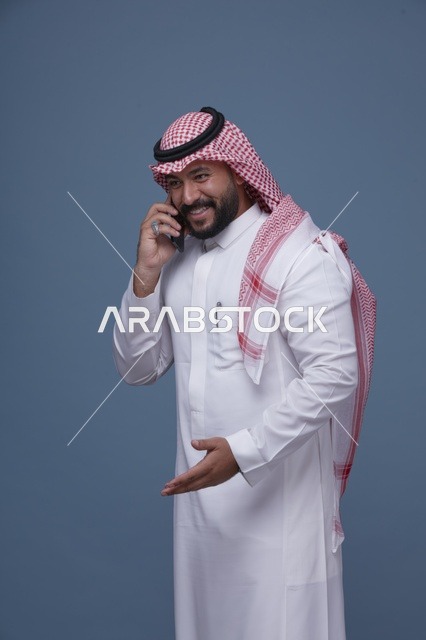 رجل سعودي مبتسم يتحدث عبر الهاتف الذكي في الاستوديو