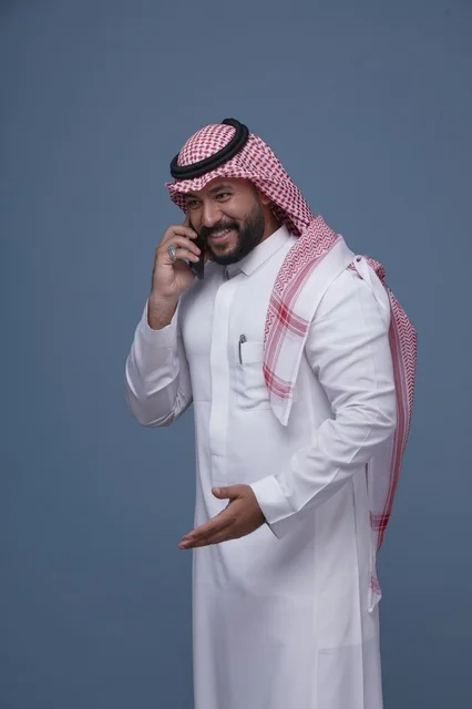 رجل سعودي مبتسم يتحدث عبر الهاتف الذكي في الاستوديو
