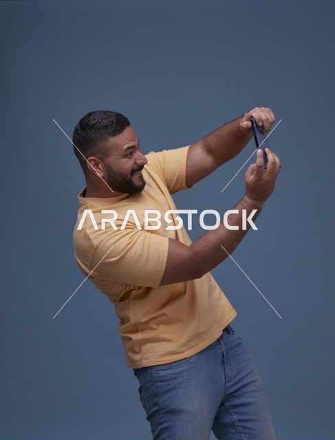 شاب سعودي يلعب بهاتفه الذكي بملابس كاجوال