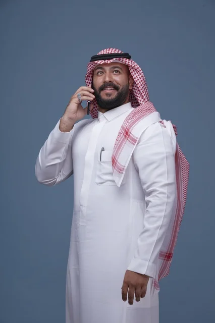 رجل سعودي بالزي التقليدي يتحدث عبر الهاتف الذكي