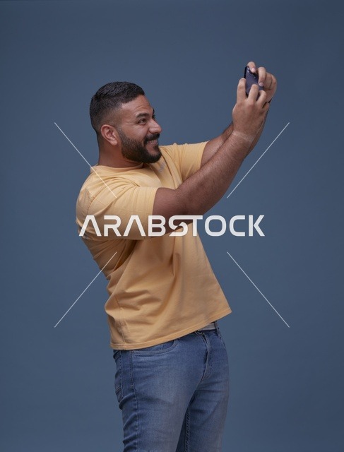 شاب سعودي يلعب على الهاتف الذكي في استوديو التصوير