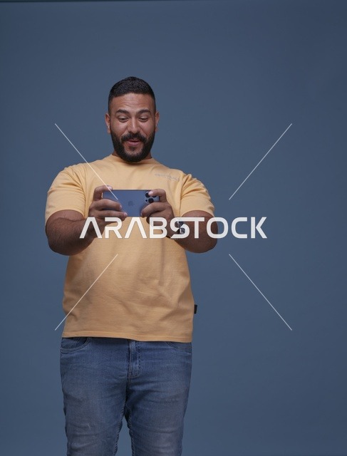شاب سعودي يلعب بالهاتف الذكي أمام خلفية زرقاء