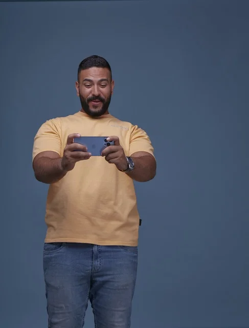 Saudi Man Playing Mobile Game on Smartphone Blue Background